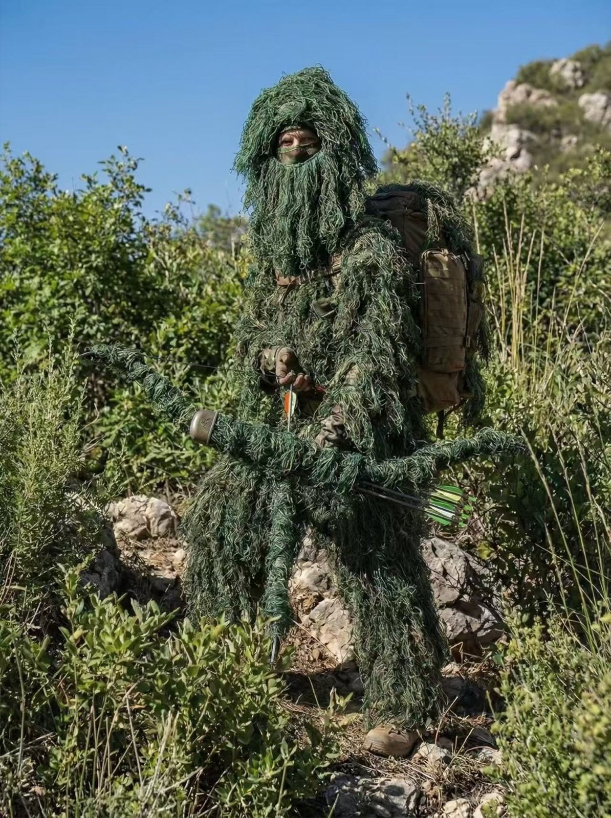 Full green ghillie suit in rocky woodland terrain